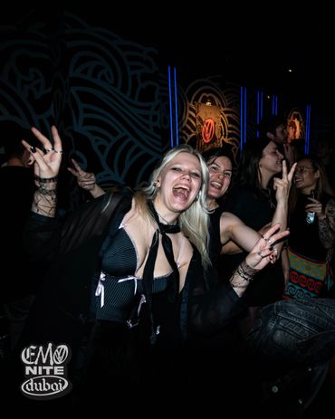 Two women joyfully posing at a lively Emo Nite Dubai event.