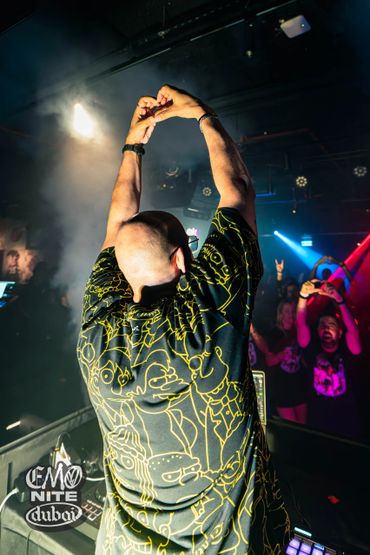 DJ making a heart gesture towards the crowd at a lively club night.