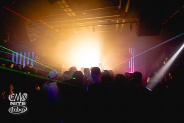 Crowd enjoying a vibrant nightclub scene with bright lights and lasers.