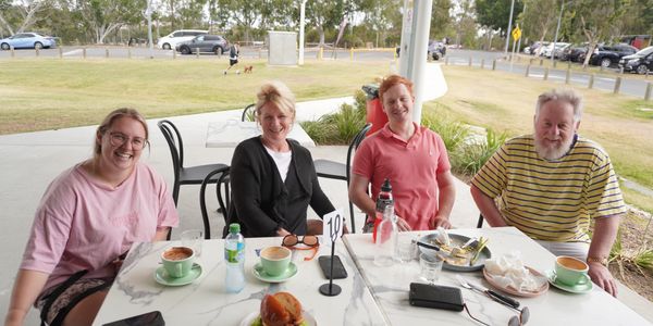 family and friends sitting together enjoying coffee and cakes