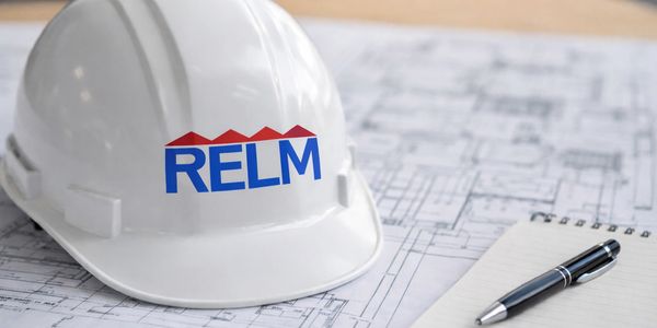 White construction helmet with RELM logo on architectural blueprints.