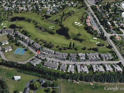Aerial view of a residential area adjacent to a golf course and tennis courts.