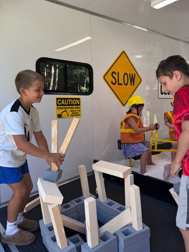 Kids playing with wooden blocks in a mock construction area.
