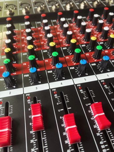 Close-up of a sound mixing console with colorful knobs and sliders.