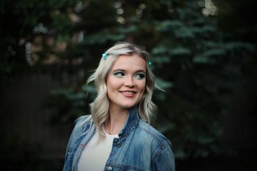 Smiling woman with blonde hair wearing a denim jacket.