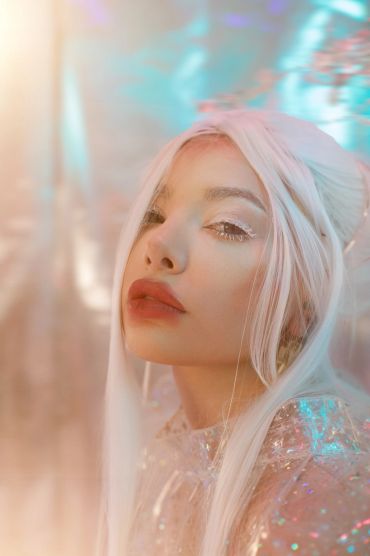 Portrait of a woman with white hair and shimmering makeup.