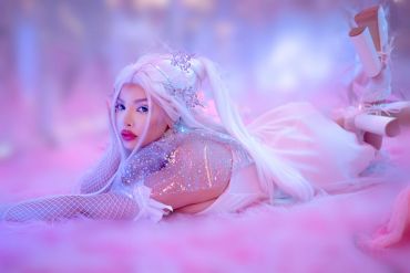 Person in white fantasy costume lying on pink floor.