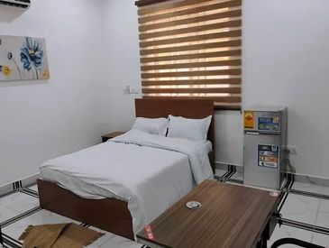 Minimalist bedroom with a bed, window blinds, and a small fridge.
