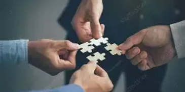Four hands connecting puzzle pieces symbolizing teamwork.