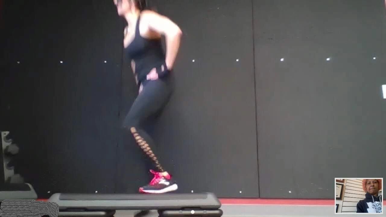 Woman exercising on a step platform in a gym setting.