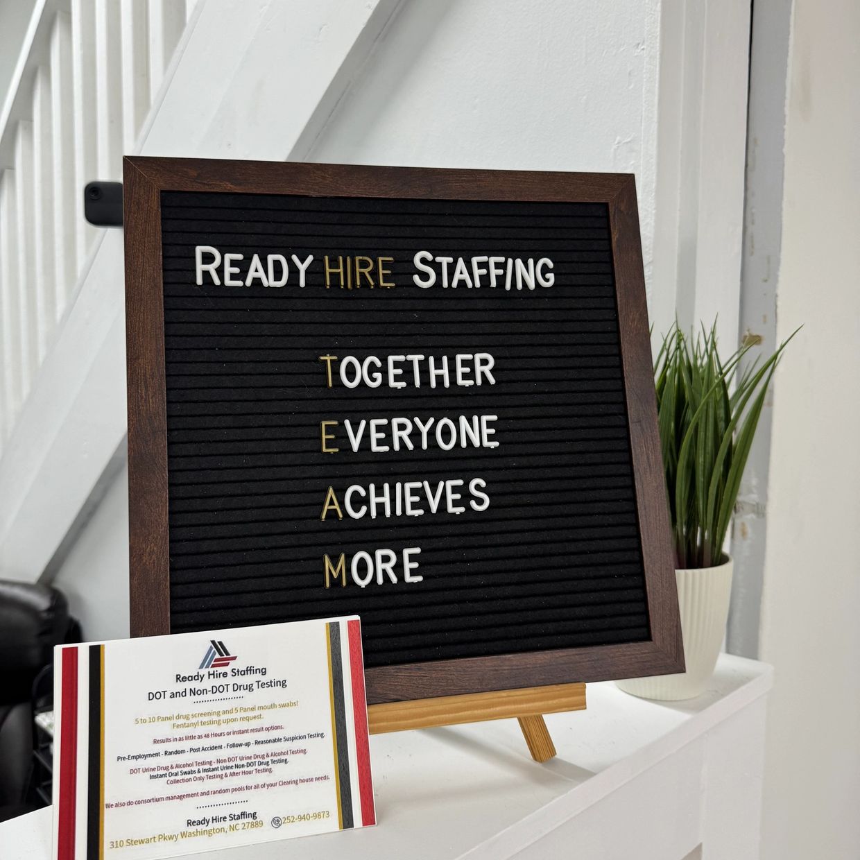 Motivational message board of Ready Hire Staffing with a plant and informational flyer.