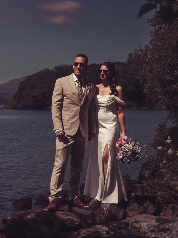 Couple in wedding attire by the lake.