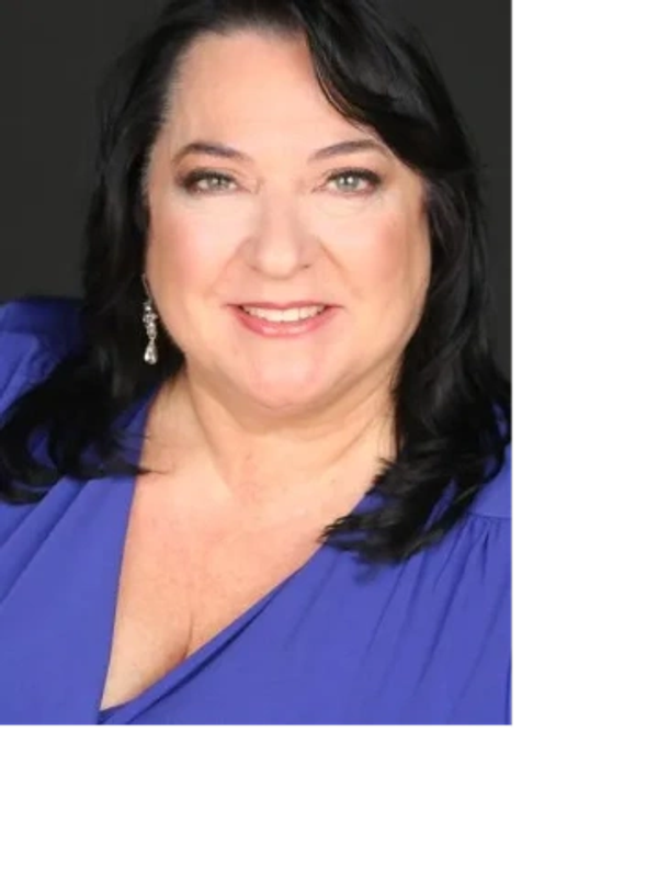 Smiling woman with dark hair wearing a blue top and dangling earrings.