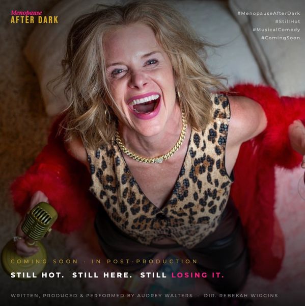 Woman laughing joyfully, holding a microphone, wearing leopard print and red fur.