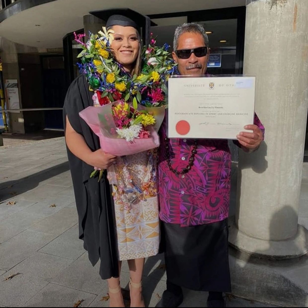 Graduate and a man holding a diploma, celebrating achievement.