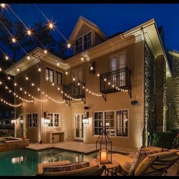 Festive string lights bistro and patio lighting on house, poolside, evening, hanging lights.