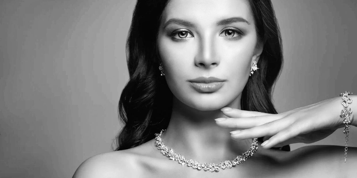 Elegant woman showcasing luxurious jewelry in black and white portrait.