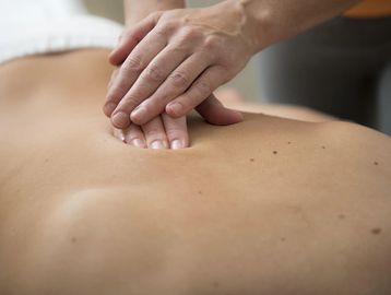 Client receiving back facial with gentle massage, relaxing in calm spa setting.