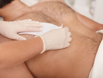 Man receiving chest waxing treatment achieving smooth, hair-free skin in relaxing spa setting.