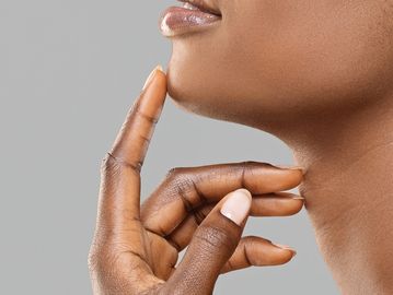 Woman touching her chin after a waxing treatment, revealing smooth, freshly treated skin. 