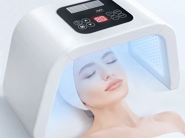 Woman under LED lamp receiving facial steam