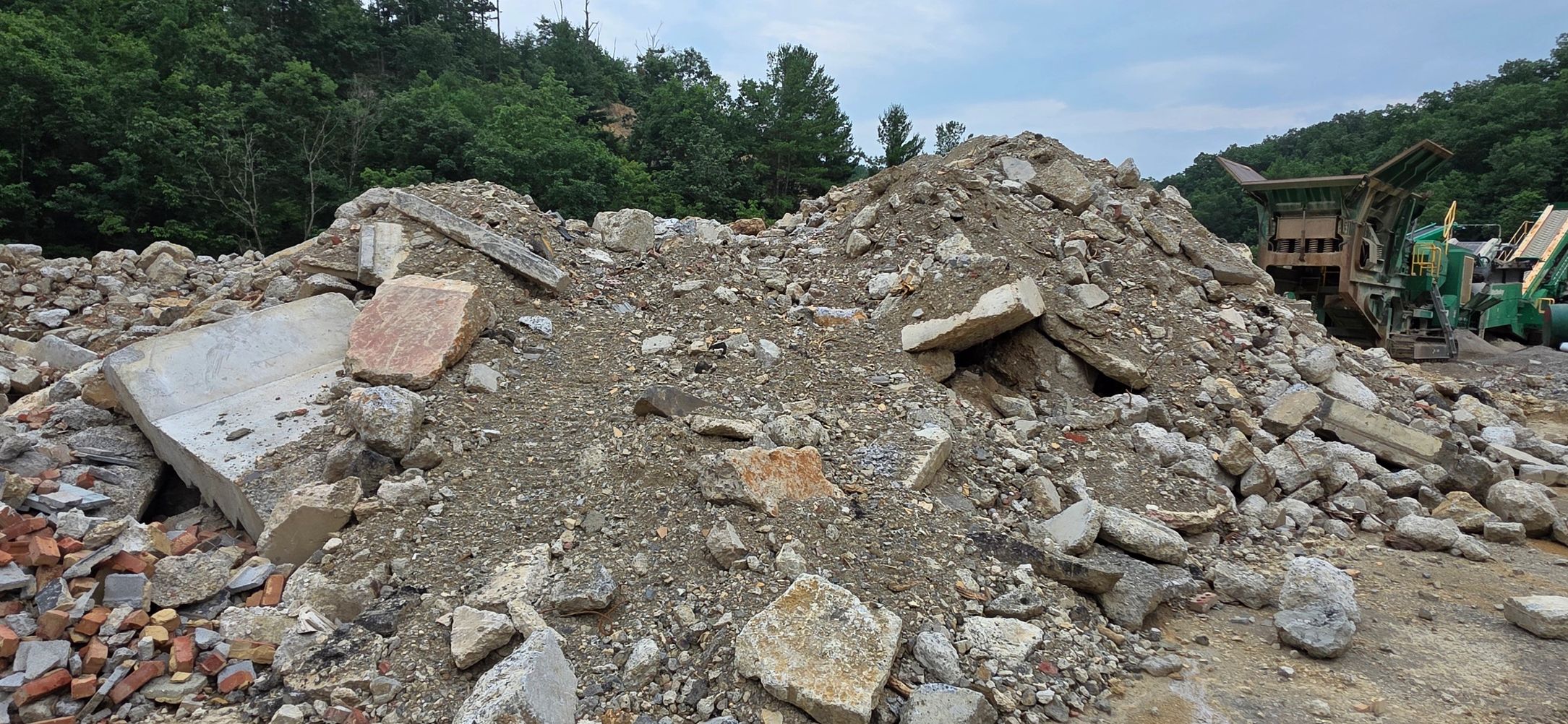 Pile of rubble and concrete debris near heavy machinery.