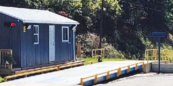 Small blue building next to a platform with yellow railings.