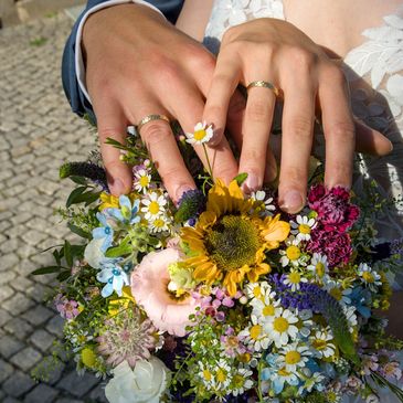 Hochzeitspaar mit Ringen und Blumenstrauß