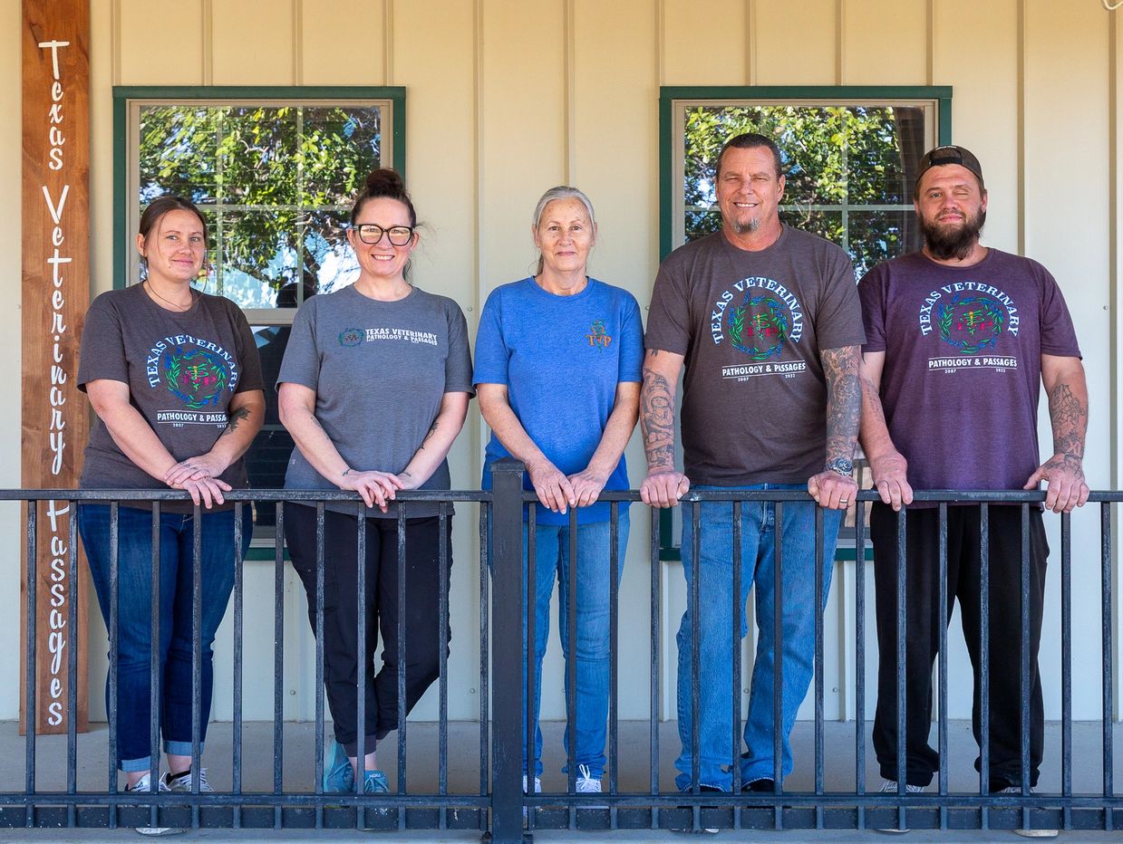Five veterinary professionals stand on a porch in front of windows at Texas Veterinary Passages.