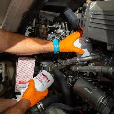 Person changing an oil filter in a Yanmar engine.