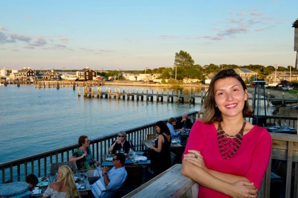 Woman in red with waterfront dining in the background.