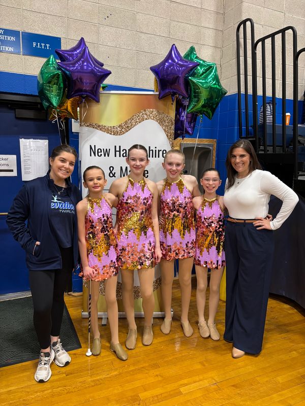Young dancers in pink and gold costumes with two women.