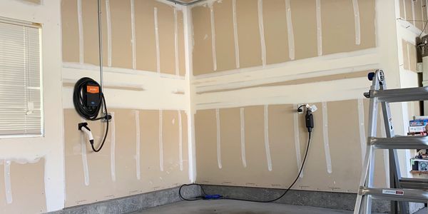 Empty garage corner with electrical outlets and a ladder.