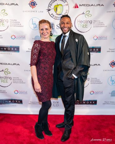 Two people posing on a red carpet at an event.