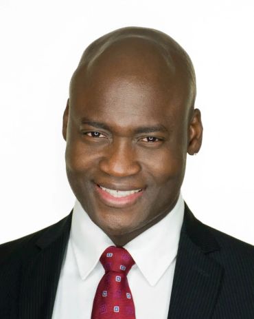 Smiling man in suit and red tie.