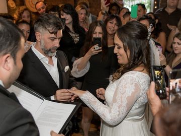 Small intimate wedding. Bride and groom putting on the ring.