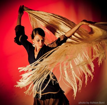 Flamenco dancer with flowing shawl on red background.