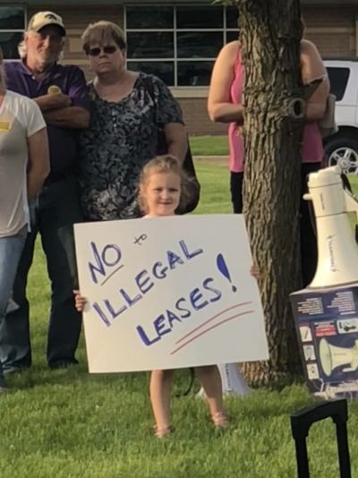 A girl holds a sign saying no to illegal leases.
