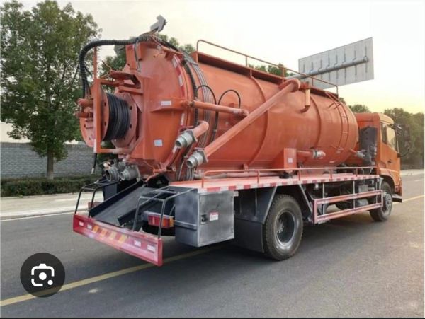 Orange industrial vacuum truck parked on the road.