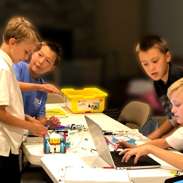 Children collaborating on a robotics project with a laptop.