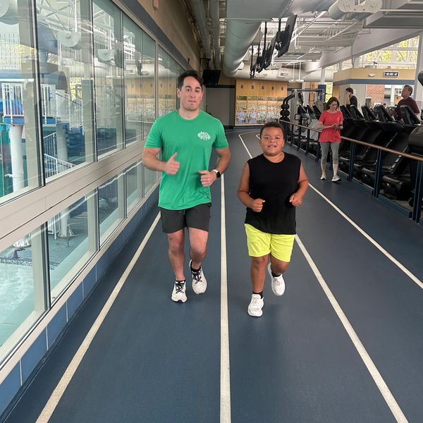 Two people jogging indoors on a track.