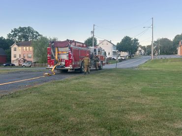 Fire truck parked on a street with firefighters preparing equipment.
