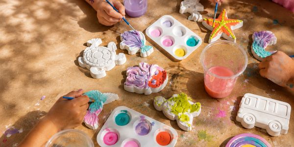 Hands painting sea animal figurines with colorful paints.
