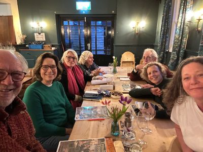Group of seven people smiling at a dinner table in a cozy restaurant.