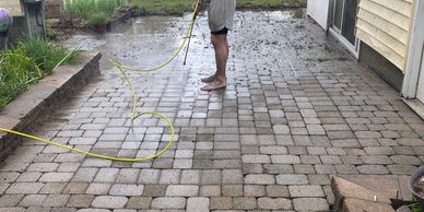 Person cleaning a patio with a hose.
