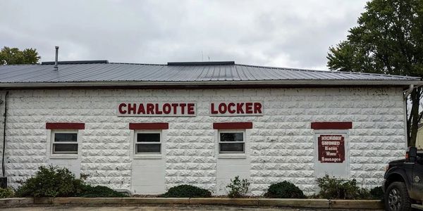 PICTURE OF WHITE CINDER BLOACK BUILDING WITH RED LETTERING LABELING THE BUILDING CHARLOTTE LOCKER