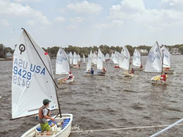 Sailboats racing on a lake under a partly cloudy sky.