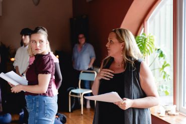 Two women engaged in a script reading session indoors.