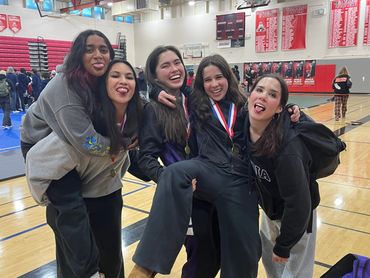 Five friends joyfully pose together in a gymnasium, celebrating a win.