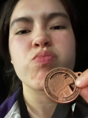 Young woman holding a coin close to her face, making a playful expression.